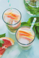 Refreshment grapefruit cocktail with mint on mint color background. Healthy citrus summer drink. Toned