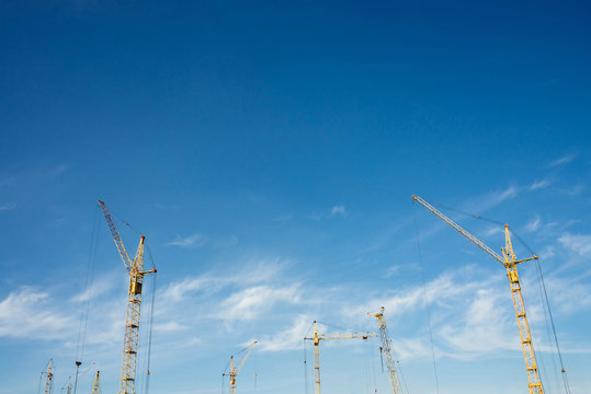 Big tower cranes against the blue sky. Background image of construction equipment close-up with copy space. Build of city.