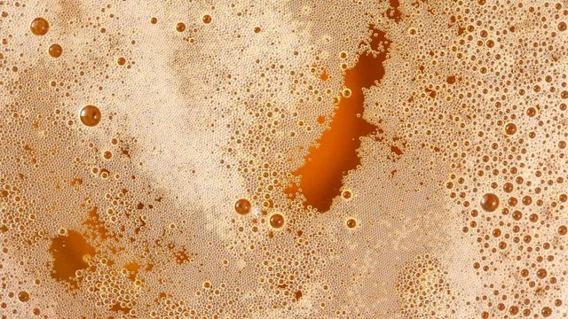 Close up of beer surface with bubbles. No sound. This file is cleaned and retouched.