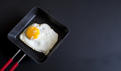 cooked eggs in pan with black wood background