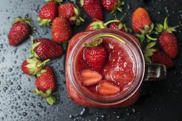 .Seasonal strawberry smoothies in a frosty glass on a black background.Top view.
