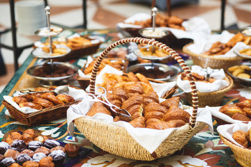 Beautifully decorated catering banquet table with variety of different pastry and bakery, with croissants and cookies on corporate christmas birthday party event or wedding celebration