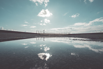 Wasserpf&uuml;tze auf Asphalt mit Reflektion des Himmels