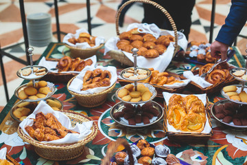Beautifully decorated catering banquet table with variety of different pastry and bakery, with croissants and cookies on corporate christmas birthday party event or wedding celebration