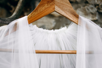 Wedding dress and boudoir of the bride hang on hangers on horns on a stone wall near the house