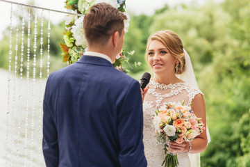 Bride with a microphone in his hands. Says the promise. Wedding ceremony. Wedding vow