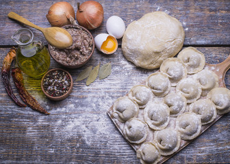 Homemade dumplings of their dough and minced meat on a wooden board, background. Top view