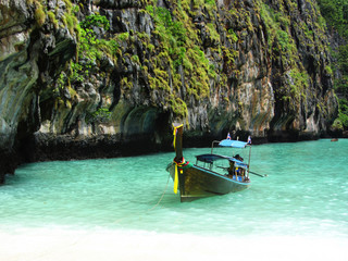 Longtale boats at the Phuket beach with limestone rock on background in Thailand. Phuket island is...