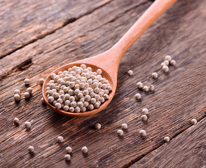 white pepper corns on wooden background
