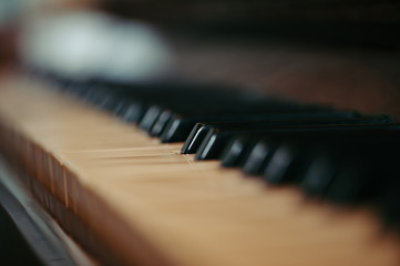 Keys of an old piano in blur. Musical ancient instrument with a wooden case. Vintage.