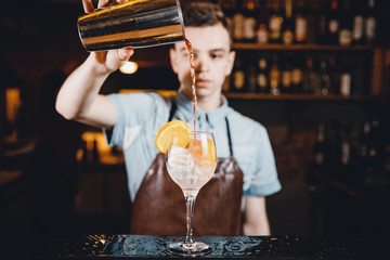 Close-up of barman mixes cocktail with ice orange, whiskey, liquor.