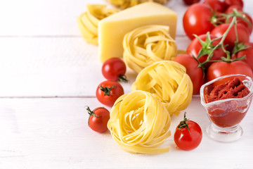 Pasta Products with Tomato Cheese Raw Pasta Fusili Fettuccine Ingredients Italian Food White Background Close Up Copy Space