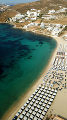 Aerial drone bird's eye view photo of famous organized with sun beds emerald clear water beach of Ornos in island of Mykonos, Cyclades, Greece