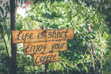 Life is short enjoy your coffee text on a wooden plate in the tropics of Bali island, Indonesia.