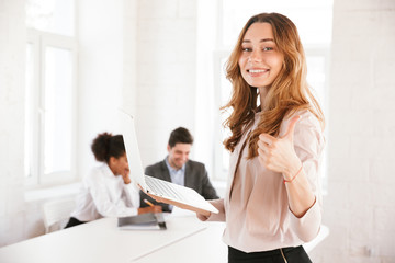 Smiling young woman showing thumbs up