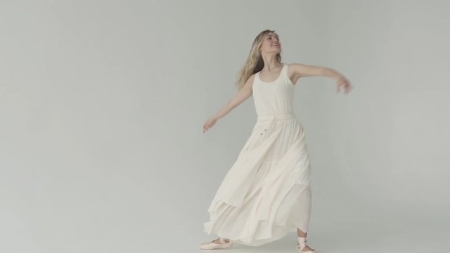 graceful young ballerina in pointe shoes and a light fluttering dress. ballet dancer on white background. slow motion