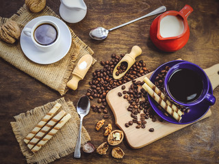 cup and coffee beans. a jug of milk. wooden background.