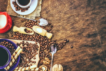 cup and coffee beans. a jug of milk. wooden background.
