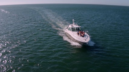 View from drone of young people relaxing on a yacht deck. Group of friends on a yacht deck on a summer day.
