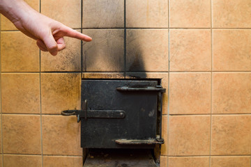 Man's hand pointing to the black soot marks from furnace on tiles wall. Problem and solution concept.