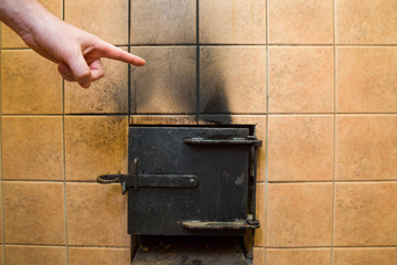 Man's hand pointing to the black soot marks from furnace on tiles wall. Problem and solution...
