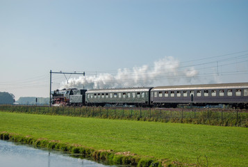 Antique steam train that drives through meadow. The Netherlands.