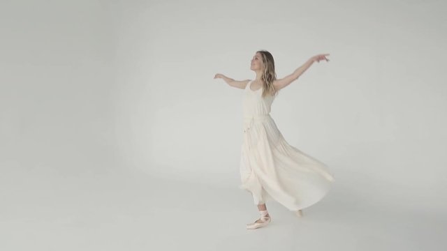 The ballet dancer is spinning and jumping high in the twine. A young ballerina dance easily and beautifully in a light fluttering dress and pointe. slow motion