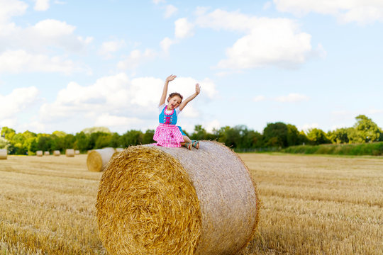 Cute little kid girl in traditional Bavarian costume in wheat field