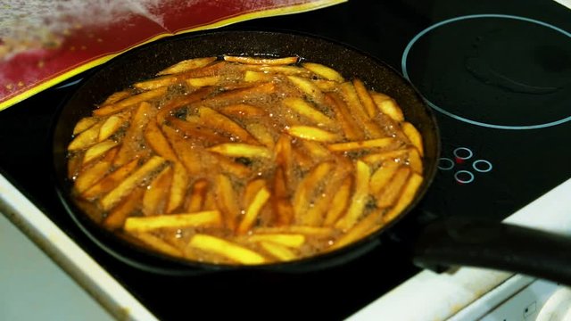 Preparation of homemade French fries. Roast the chopped potatoes in a deep frying pan in large amounts of butter.