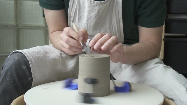 Potter carves a notch on the bottom of the pottery on a rotating circle. With help of a special tool male artisan makes recess of ceramic cup for stability.
