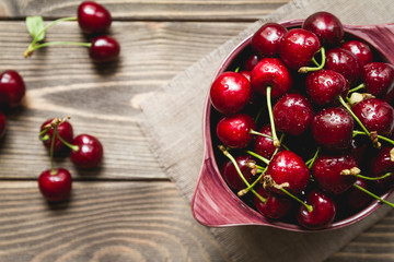 Sweet fresh cherries in a bowl on a table, top view
