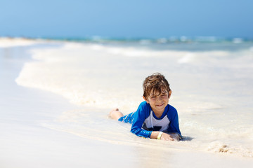 little blond kid boy having fun on tropical beach of Jamaica