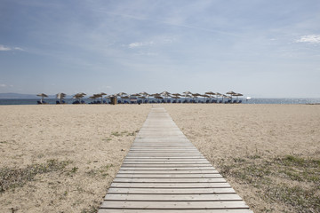 Fototapeta na wymiar wooden boards ,walkway for beutiful sand beach with sun-beds
