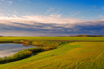 Fototapeta na wymiar field with lake on sunset in Latvia on cloudy sky background