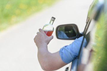 Alcohol, bottle,  car and concept of drunk driving - the person holds in hand a bottle with alcoholic drink, driving the car.
