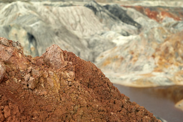 Fototapeta na wymiar landscape of a multi-colored weathered hilly desert with a poisonous lake with red water
