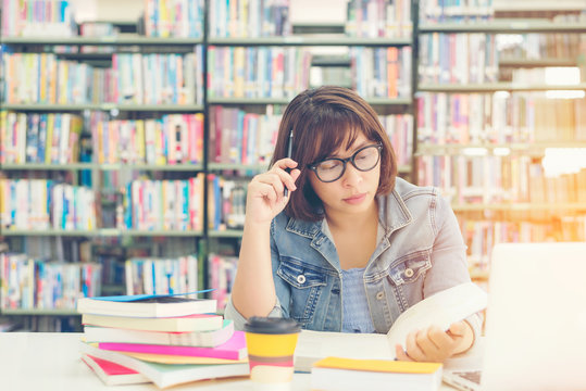 Asian women in library reading and thinking something in a book in a library.  Education  Concept