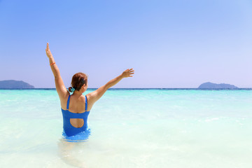 Woman in blue swiming suite raised hands up with happy in summer and beautiful sea