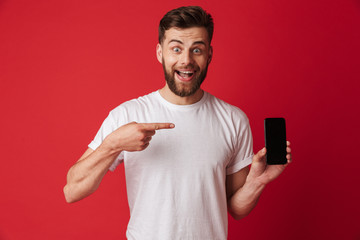 Excited young man using mobile phone pointing.