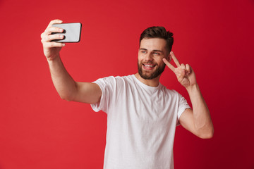 Young man standing isolated make selfie by mobile phone make peace gesture.