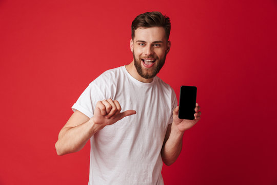 Excited young man using mobile phone pointing.