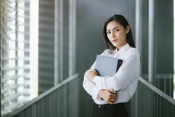  Young businesswoman standing and embracing a file