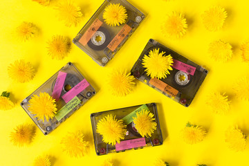 Many Audio cassettes on a yellow background with a pattern of dandelions. Inscriptions on the tape. Concept of nostalgia. Creative layout. Copy space. Flat lay