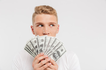 Portrait of a surprised teenage boy holding money banknotes