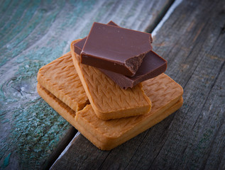 A stack of cookies and chocolate on a wooden background