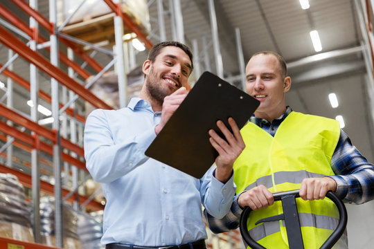 logistic business, shipment and people concept - businessman with clipboard and warehouse worker with loader