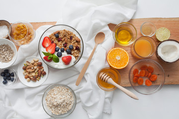 Ingredients for a healthy breakfast - granola, honey, nuts, berries, fruits, top view.