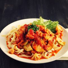 Ribbon pasta with Arrabiata sauce. Close up. Mediterranean dish. Tagliolini pasta with vegetables. Cauliflower, courgette and tomato stew. Italian cuisine. Vegan and vegetarian. Toned photo.