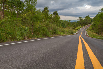 Beautiful mountain asphalt road with curve and double yellow line ,  road runs along the edge of the forest in chiang mai, Thailand