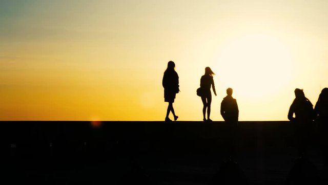 Silhouettes of people in the photo session, the girl is shooting at sunset